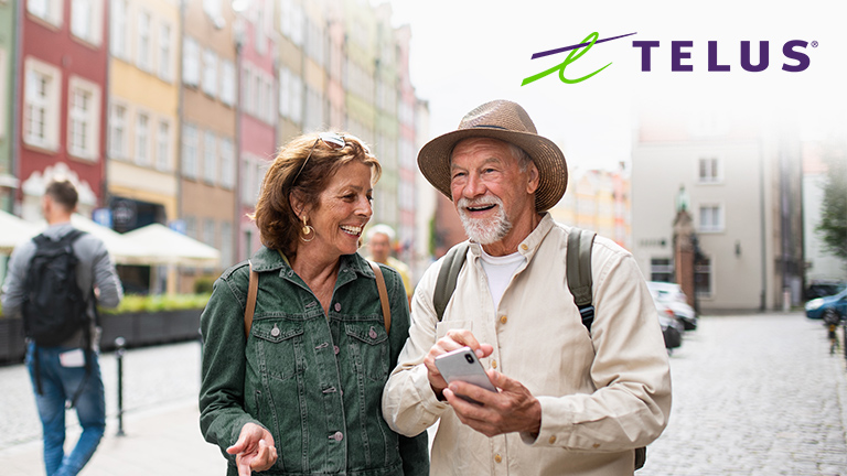 Couple marchant dans la rue et utilisant leur téléphone avec le logo de TELUS