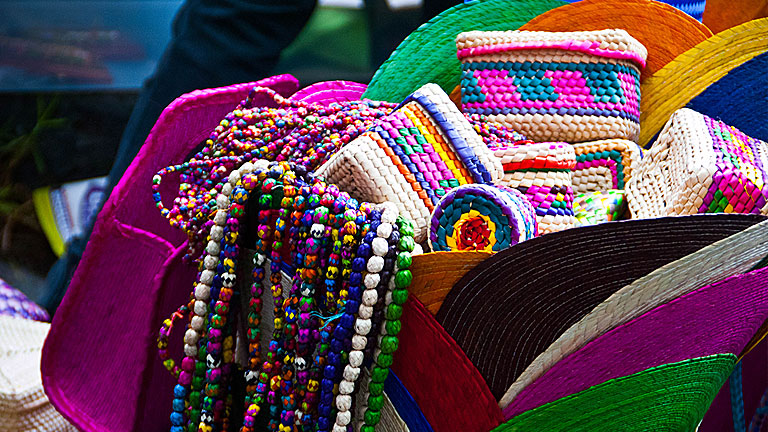 A brightly coloured basked filled with local handmade goods and beaded necklaces.