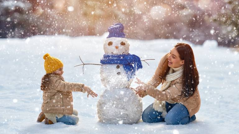 Une mère et son enfant faisant un bonhomme de neige