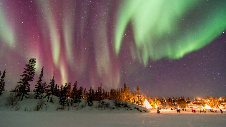 Aurora borealis over tepees.